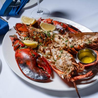 Grilled lobster served with lemon wedges and a side of melted butter.