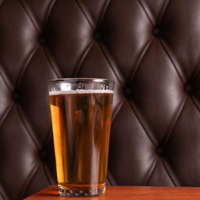 Pint glass filled with beer and served on the table.