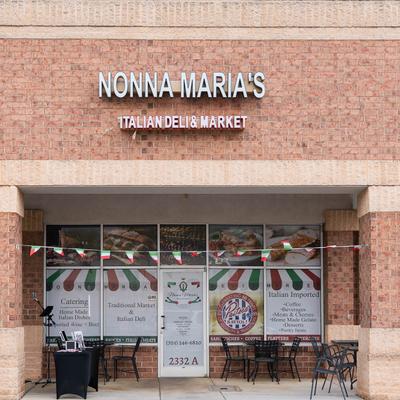 Facade of Nonna Maria's Italian Deli & Market in a brick building, Outdoor tables and Italian flag bunting.