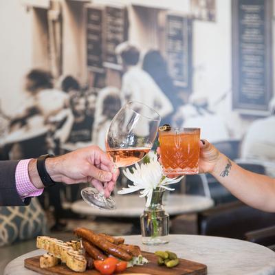 Interior, guests making a toast with drinks over a table with served food.