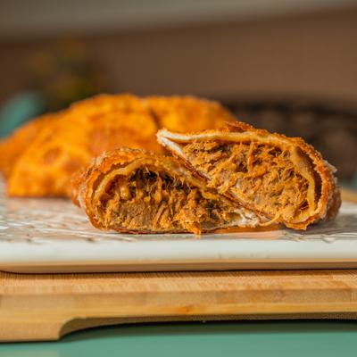Close-up of a cut empanada showing shredded beef filling.