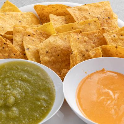Tortilla chips served alongside green and orange dips.