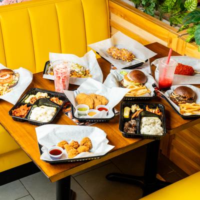 Table spread featuring various dishes and drinks in a booth with yellow seating.