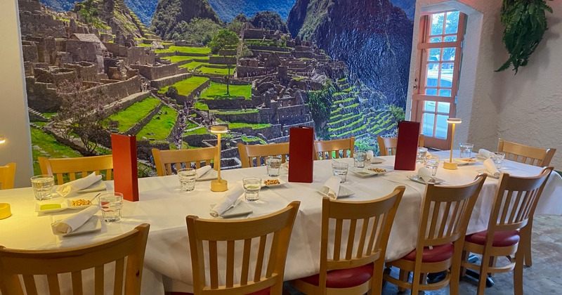A long table set for dining in front of a wall decorated with a poster of Machu Picchu