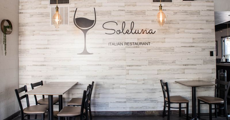 Interior, two tables and chairs and a SoleLuna Beverage sign on the wall