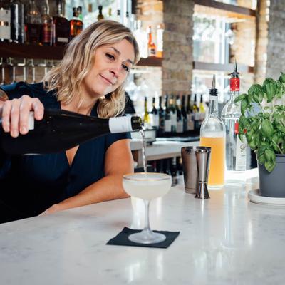 Bar area, bartender pouring sparkling wine in a coupe glass