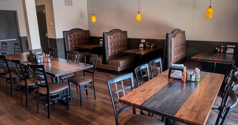 Interior of dining area with dining tables, chairs, and upholstered booths along the wall