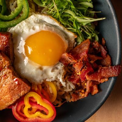 Protein bowl featuring pork belly and a fried egg, close-up.