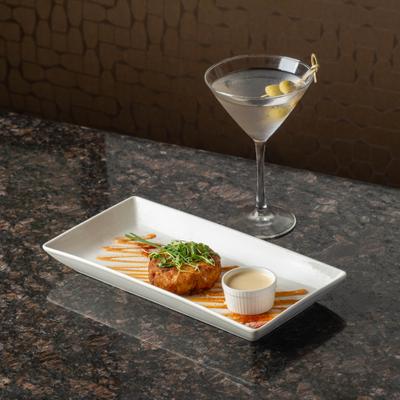 Blue crab cake with dipping sauce beside a dirty martini.