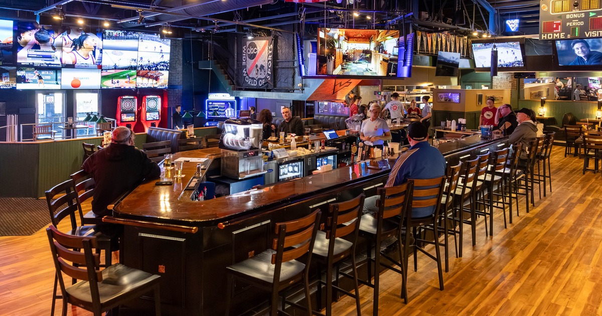 Bar area with a long counter seating and televisions