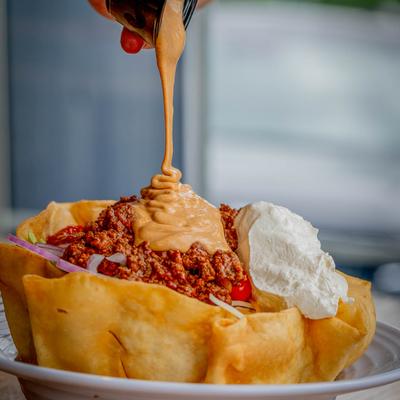 Sauce being poured on a taco salad.