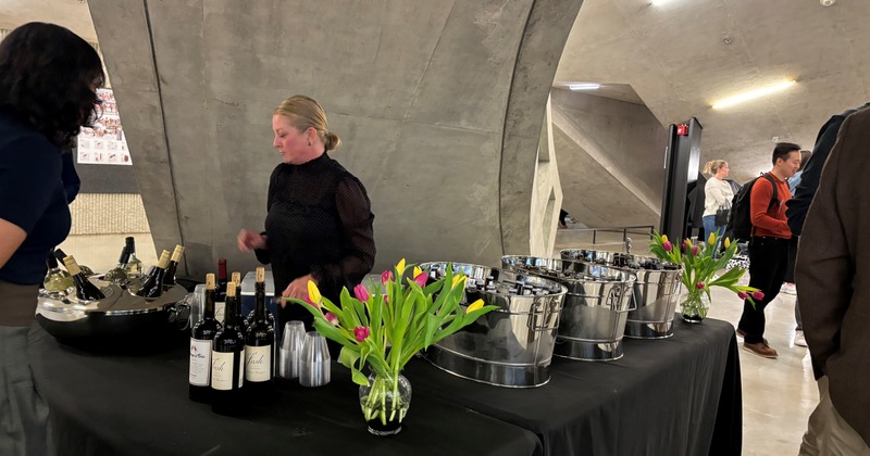 Catering table with wine bottles, ice buckets and flower arrangements