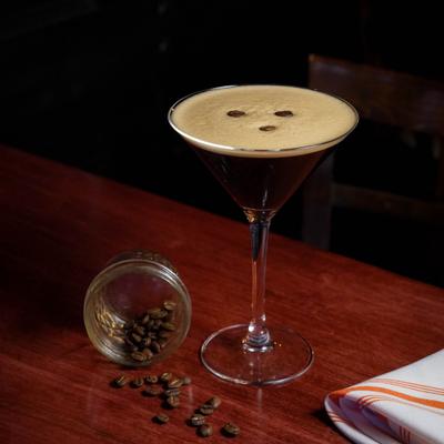 Espresso Martini alongside roasted coffee beans scattered on a table.