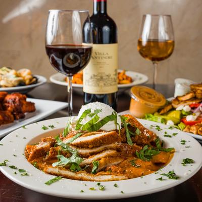 Stuffed rigatoni plate on a table with other dishes, a bottle of wine, and wine glasses.