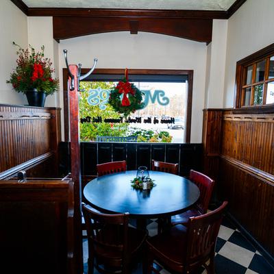 Cozy restaurant corner with a round table, wood paneling, and festive decorations.