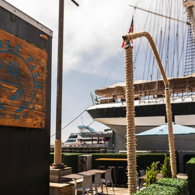 Outdoor deck featurnig seating area and a view of the waterfront and a restaurant sign.