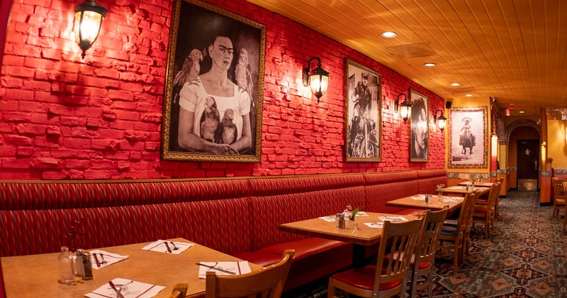 Interior, dining area, long banquette bench with tables, red brick wall with paintings