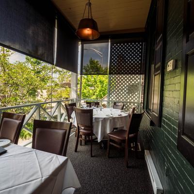 Balcony seating area with set tables, surrounded by trees.