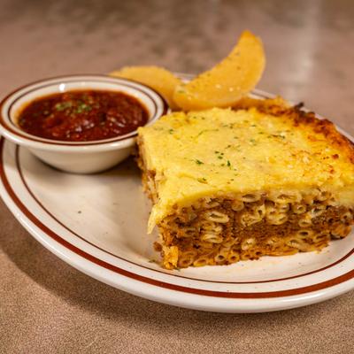 Greek pasta bake served with potatoes and a small bowl of chili.