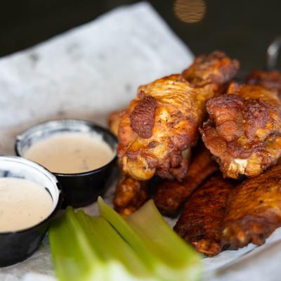 Smoked chicken wings with two sauces and celery sticks on the side