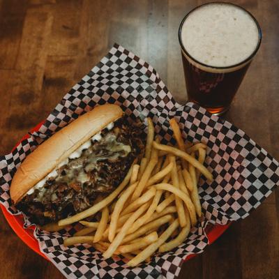 Philly cheesesteak, with fries, and a glass of beer.