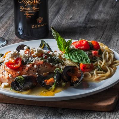 Grilled salmon with mussels, pasta, spinach, tomatoes, and feta cheese.