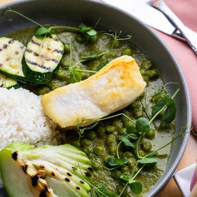 Grilled white fish with rice, zucchini, and peas in green sauce.