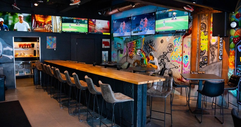 One long tall table, bar stools and TV on the wall