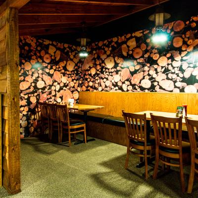 Interior, a restaurant scene with wooden booths and wood logs wallpaper.
