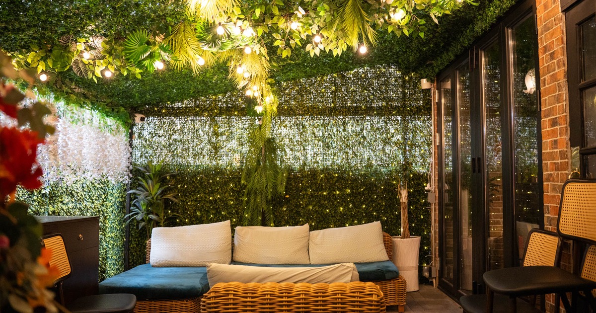 Exterior, covered lounge area, corner wicker sofa and armchair, plant decoration