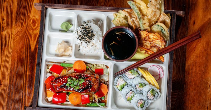 Grilled meat, vegetables, sushi, rice and dip on the side closeup