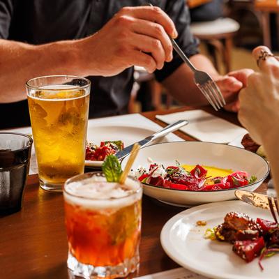 People enjoying a meal at a restaurant table, featuring colorful dishes and drinks.