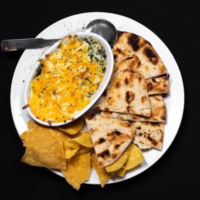 Spinach and artichoke dip served with flatbread and tortilla chips.