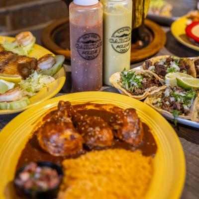 Mole Ranchero served with tacos, condiments, and other dishes.