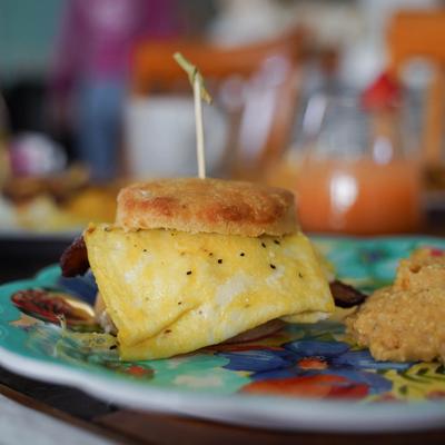 Bacon and egg sandwich on a biscuit, served with grits.