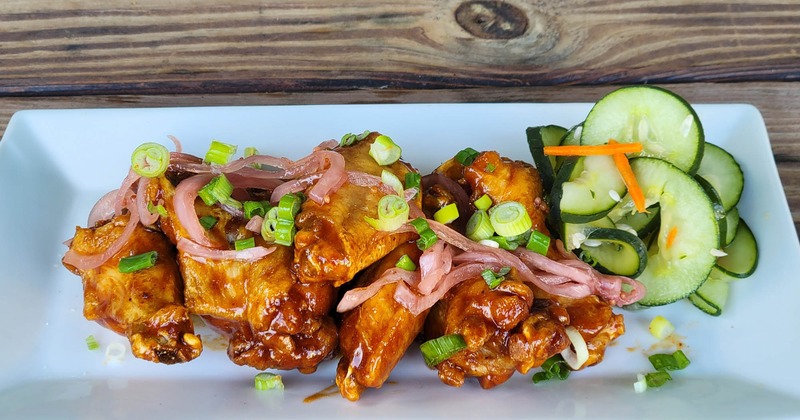Glazed chicken wings with green onions and pickled veggies