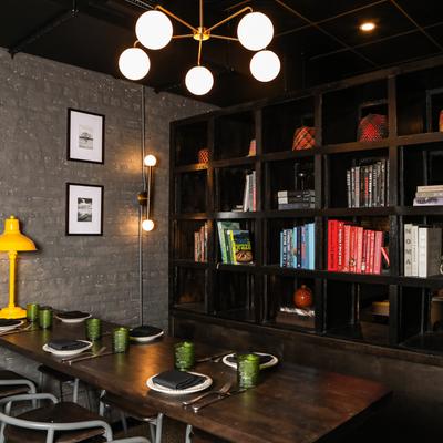 Interior with a set table, brick walls, hanging lights and black shelves filled with books.