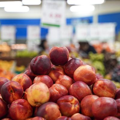 A pile of fresh peaches in the grocery store produce section.