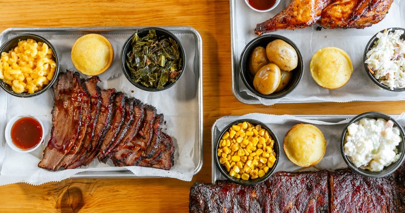 Table spread featuring sliced brisket, ribs, cornbread, mac and cheese and collard greens