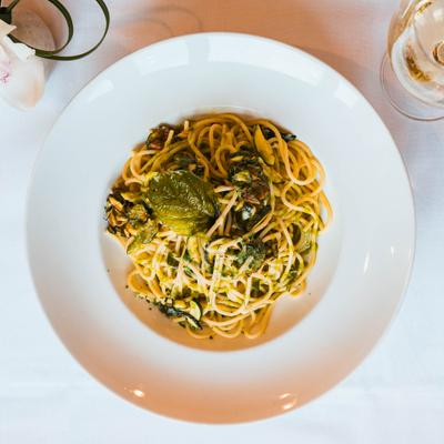 Spaghetti with zucchini and herbs in a white bowl.