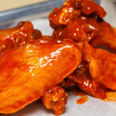 Buffalo wings coated in a red sauce.