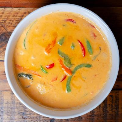 Red Curry bowl on a wooden table, top down view.
