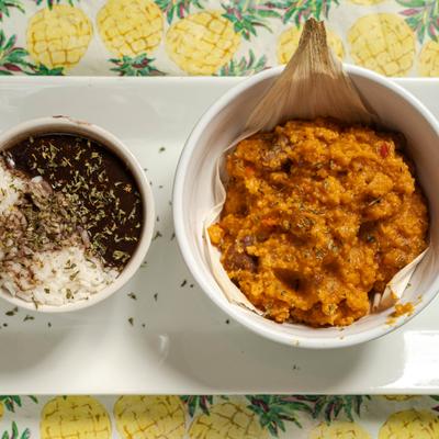 Pork corn tamales served with a side of black beans and rice, top view.