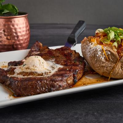 Grilled steak with butter, served with baked potato.