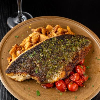 Fish fillet served with polenta potatoes, roasted tomatoes and salsa slow-verde.