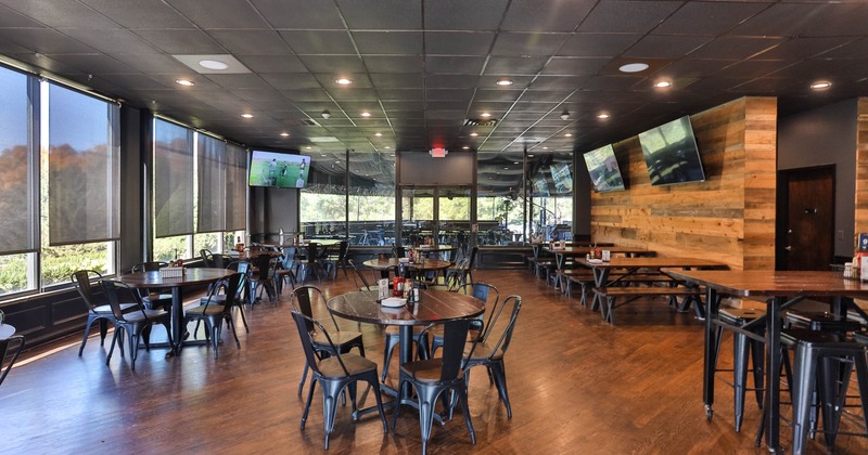 Interior with wooden floors, dark metal chairs, and flat-screen TVs on the wall