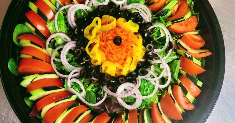 Circular shaped salad of greens, vegetables and olives