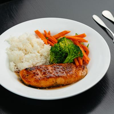 Broiled salmon served alongside rice, carrots, and broccoli.