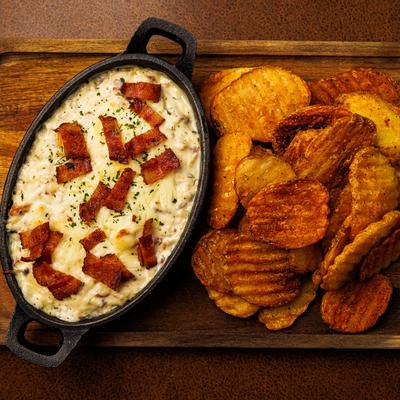 Chicken bacon ranch dip with potato chips on a wooden board.