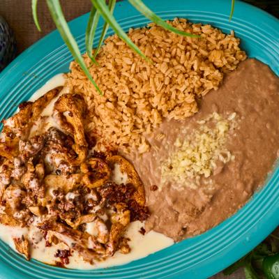 Overhead view of chicken and chorizo with rice and refried beans.